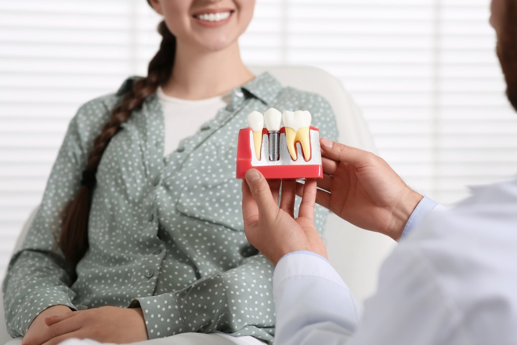 Dentist showing woman a dental implant example